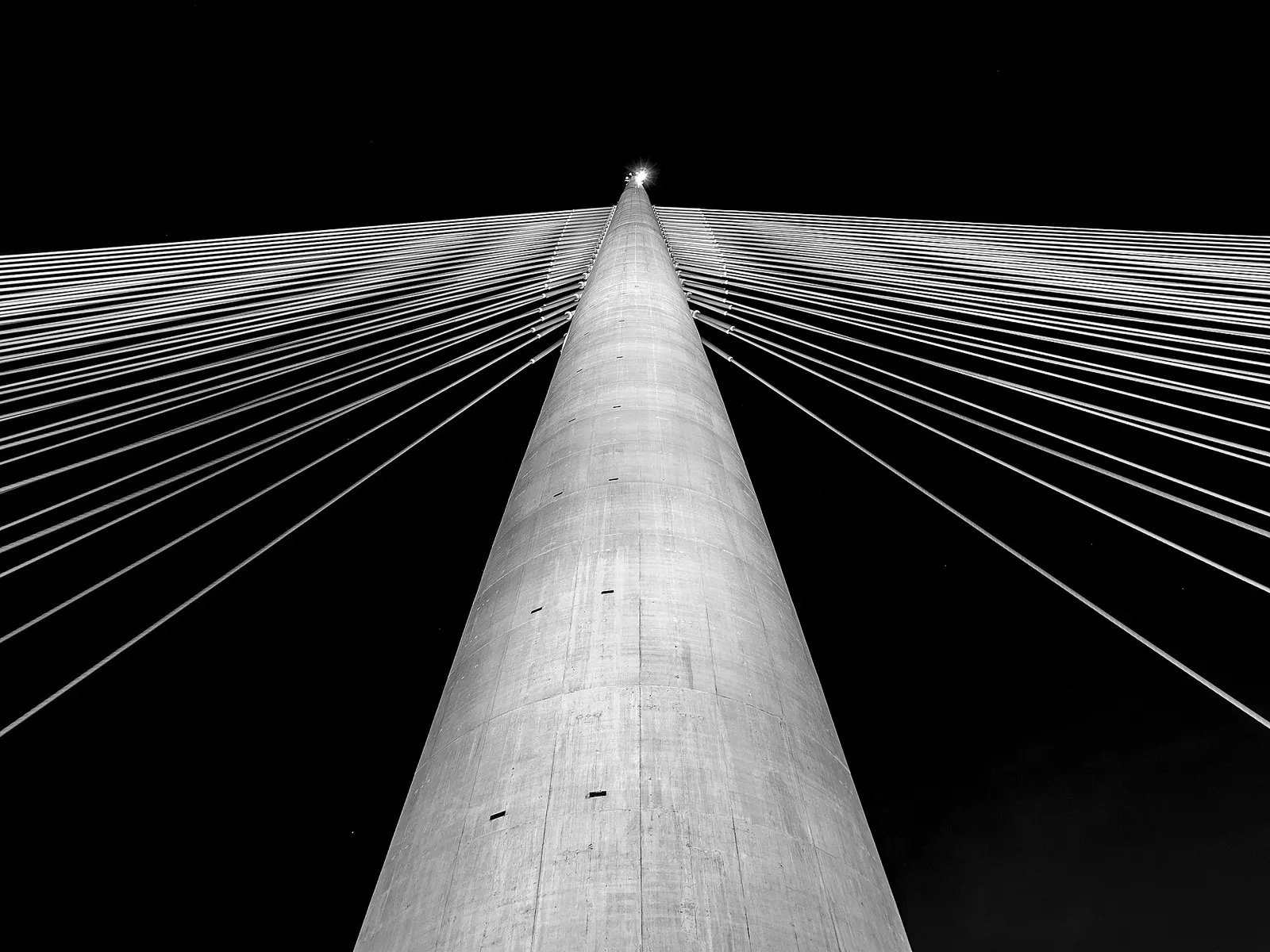 Hochspannungsmast mit Stromleitungen vor bewölktem Himmel